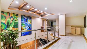 Um interior moderno com uma escada, um corrimão de madeira e duas pinturas abstratas na parede.