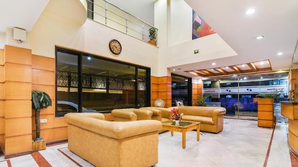 A spacious lobby with a high ceiling, a large sofa set, a coffee table, and a reception desk. - Grand Plaza (Coimbatore)
