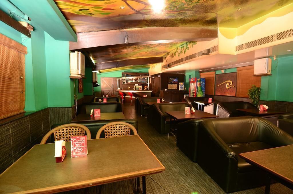 A restaurant with booths and tables, a bar area, and a ceiling with a mural.