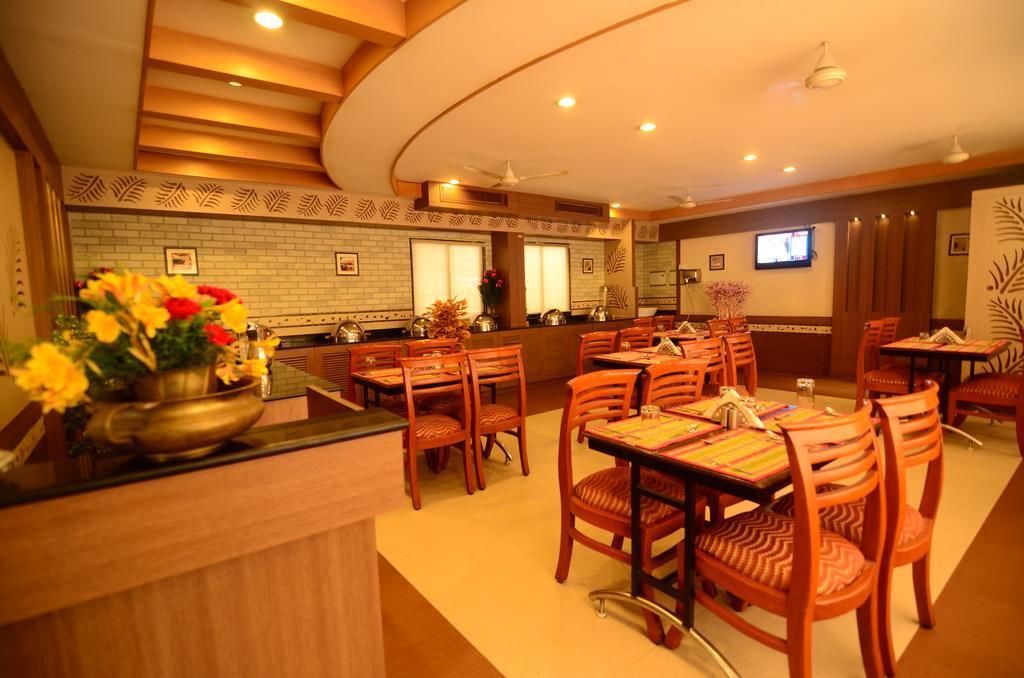 Ein Restaurant mit Holztischen, einer Theke mit Blumen und einem Fernseher an der Wand.