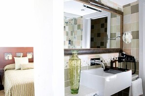 A hotel room with a bed, a bathroom with a sink and mirror, and a tiled wall. - Mar d'Espills (Amposta)