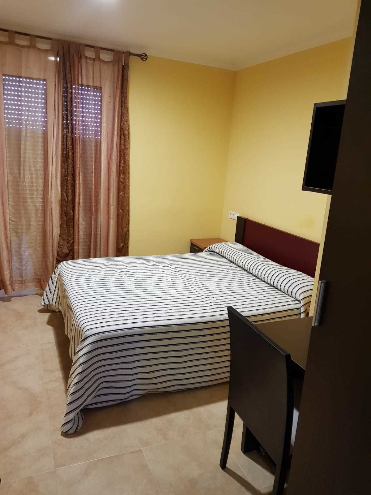 Un dormitorio con cama, escritorio y televisor.