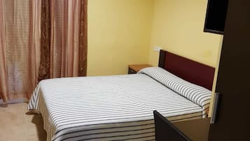 Un dormitorio con cama, escritorio y televisor.