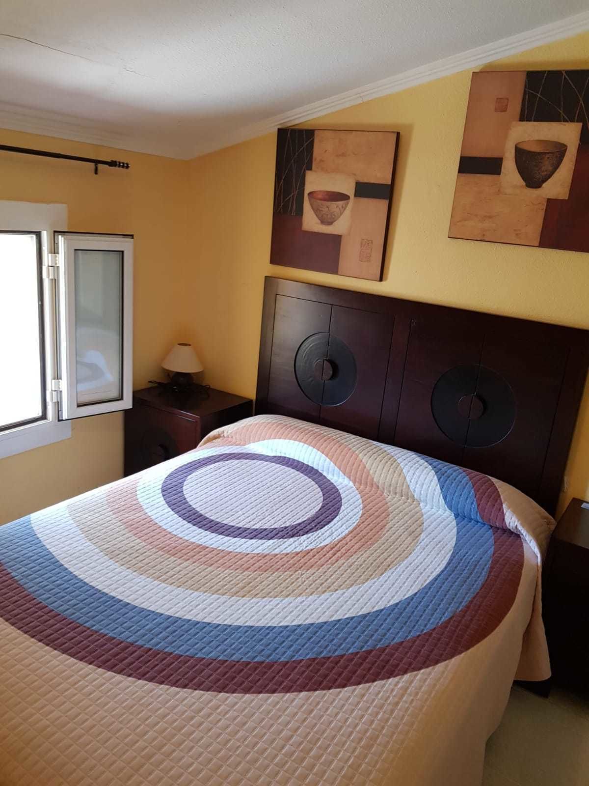 Una habitación de hotel con una cama, una mesita de noche, una lámpara y obras de arte en la pared.