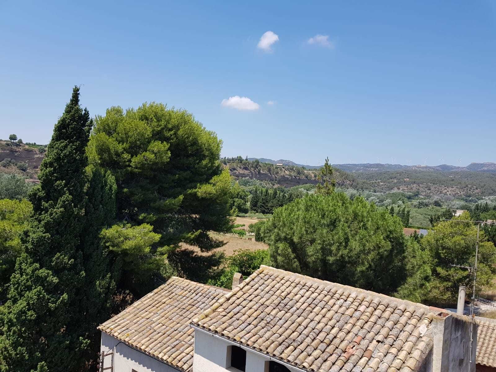 Un paysage rural avec un bâtiment doté d’un toit en tuiles et offrant une vue sur la campagne environnante.