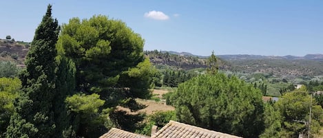 A rural landscape with a building featuring a tiled roof and a view of the surrounding countryside.