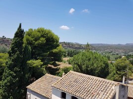 Paisaje rural con un edificio de techo a tejas y vistas del campo circundante.