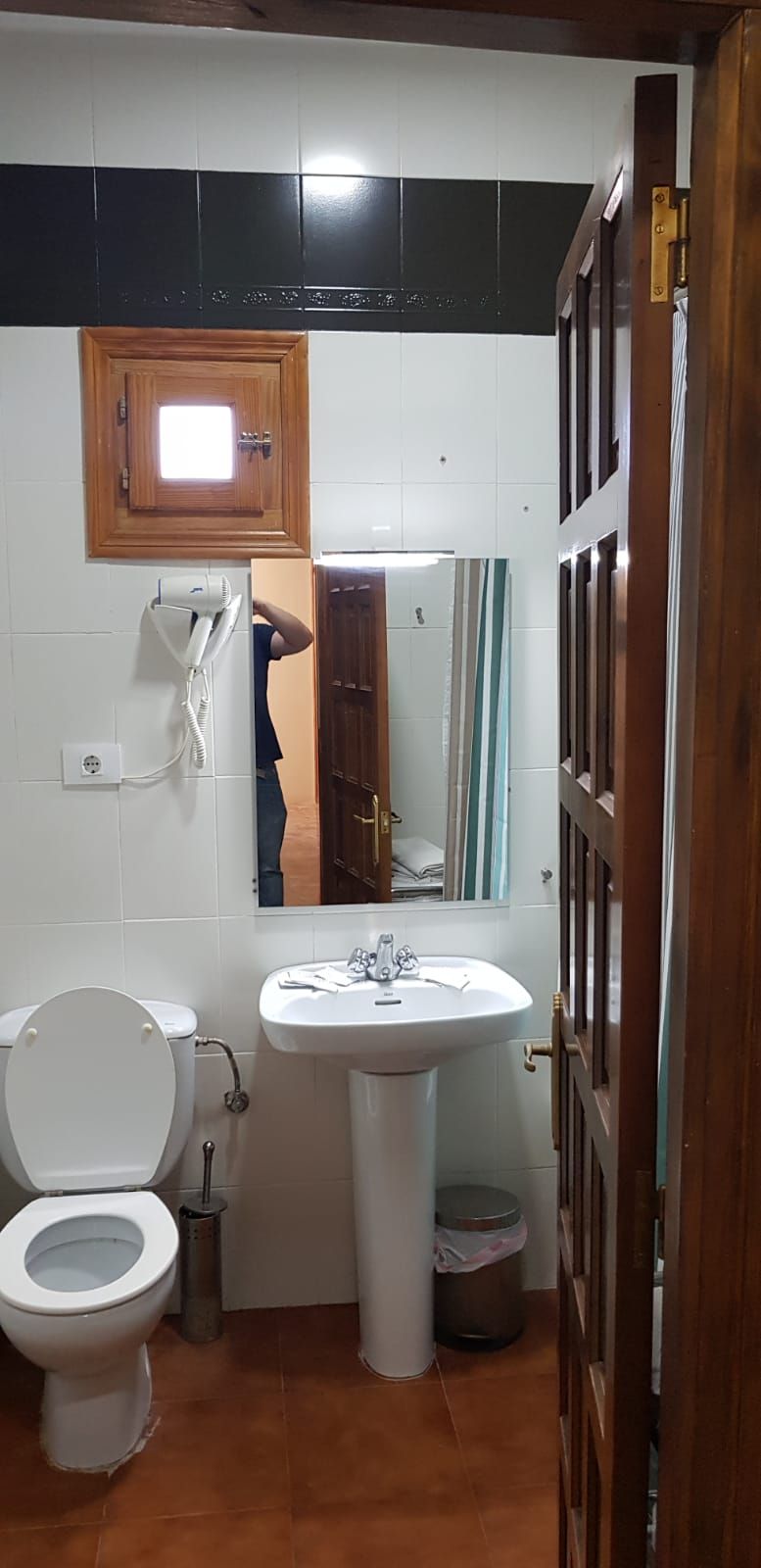 A small bathroom with a toilet, sink, and a mirror above the sink.