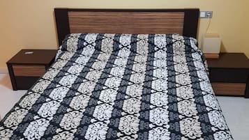 A bed with a black and white patterned bedspread, two bedside tables, and two wall-mounted lamps.