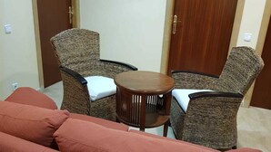 A room with a red sofa, two wicker chairs, a small round table, and two wooden doors. - Hotel Mas Subirats (Mora la Nova)