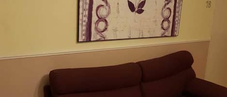Una sala de estar con un sofá marrón y una obra de arte enmarcada en la pared.