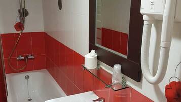 Un baño con bañera, lavabo, espejo y porta papel higiénico.