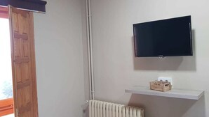 A room with a mounted TV, a radiator, and a wooden crate on a shelf. - Hotel Mas Subirats (Mora la Nova)