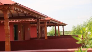 Un edificio con fachada roja y un porche cubierto con columnas de madera.