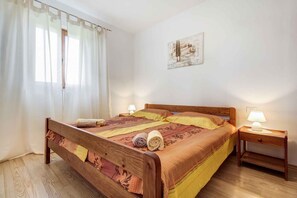 A neatly made bed with a wooden headboard, two bedside lamps, and a painting on the wall.