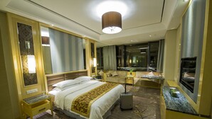 Een hotelkamer met een groot bed, een bureau, een stoel, een televisie en een spiegel in de badkamer.