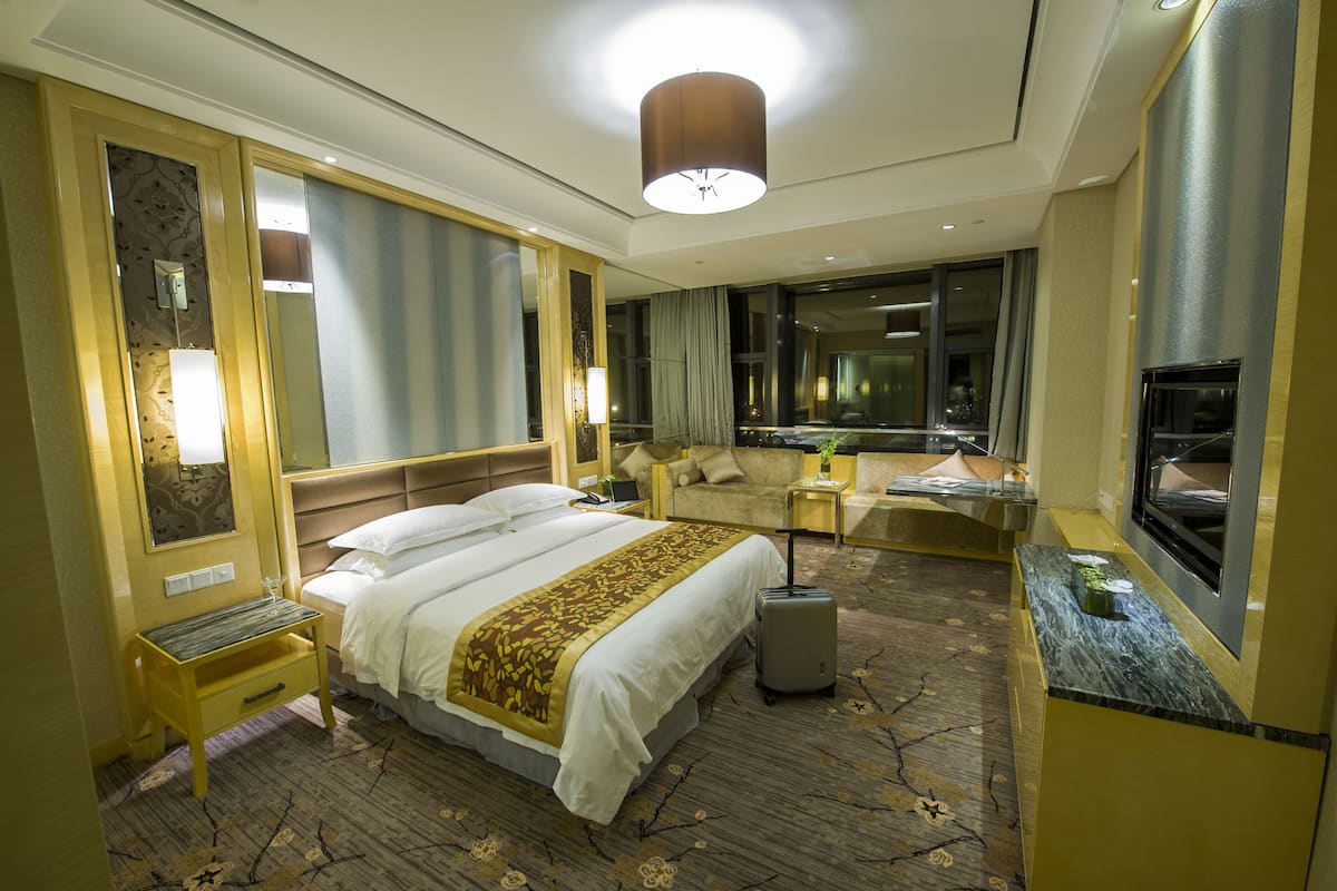 Ein Hotelzimmer mit einem großen Bett, einem Schreibtisch, einem Stuhl, einem Fernseher und einem Spiegel im Badezimmer.