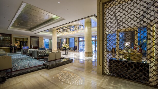 Een ruime lobby met een hoge plafond en een centraal gelegen zitgedeelte, evenals een decoratief glazen plafond.
