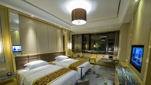 Hotelkamer met twee bedden, een bureau, een televisie en een groot raam.