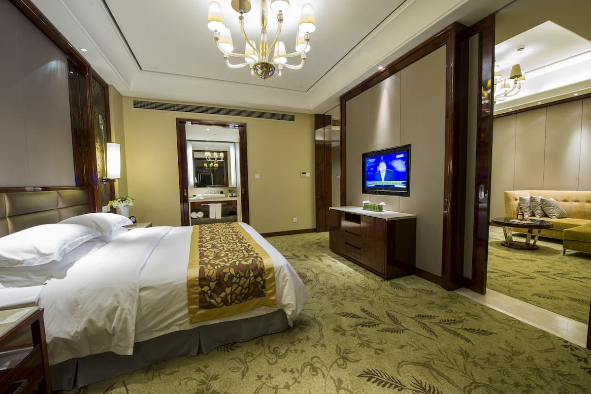 Ein Hotelzimmer mit einem großen Bett, einem Fernseher, einem Schreibtisch und einer Couch.