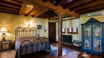 A bedroom with a bed, wooden beams, a radiator, a cabinet with paintings, and a lamp.