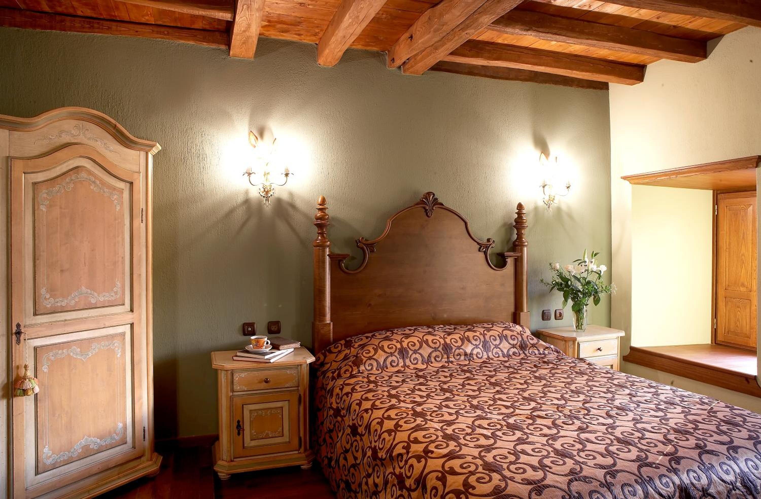 Un dormitorio con una cama de madera, dos mesitas de noche, un armario y una lámpara de pared.