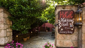 A stone wall entrance with a sign for Hotel Kakkino Spiti, featuring a contact number and the phrase "Luxury living".