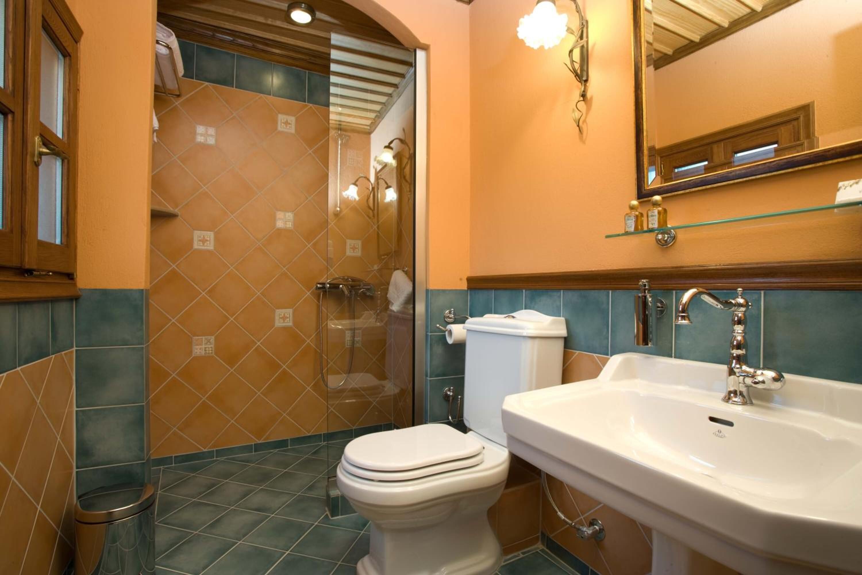 Un baño con ducha, inodoro, lavamanos y un estante de vidrio sobre el lavamanos.