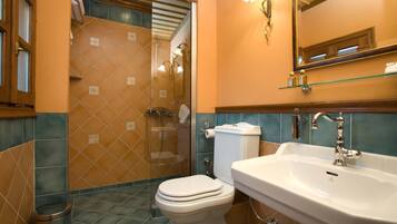 Un baño con ducha, inodoro, lavamanos y un estante de vidrio sobre el lavamanos.