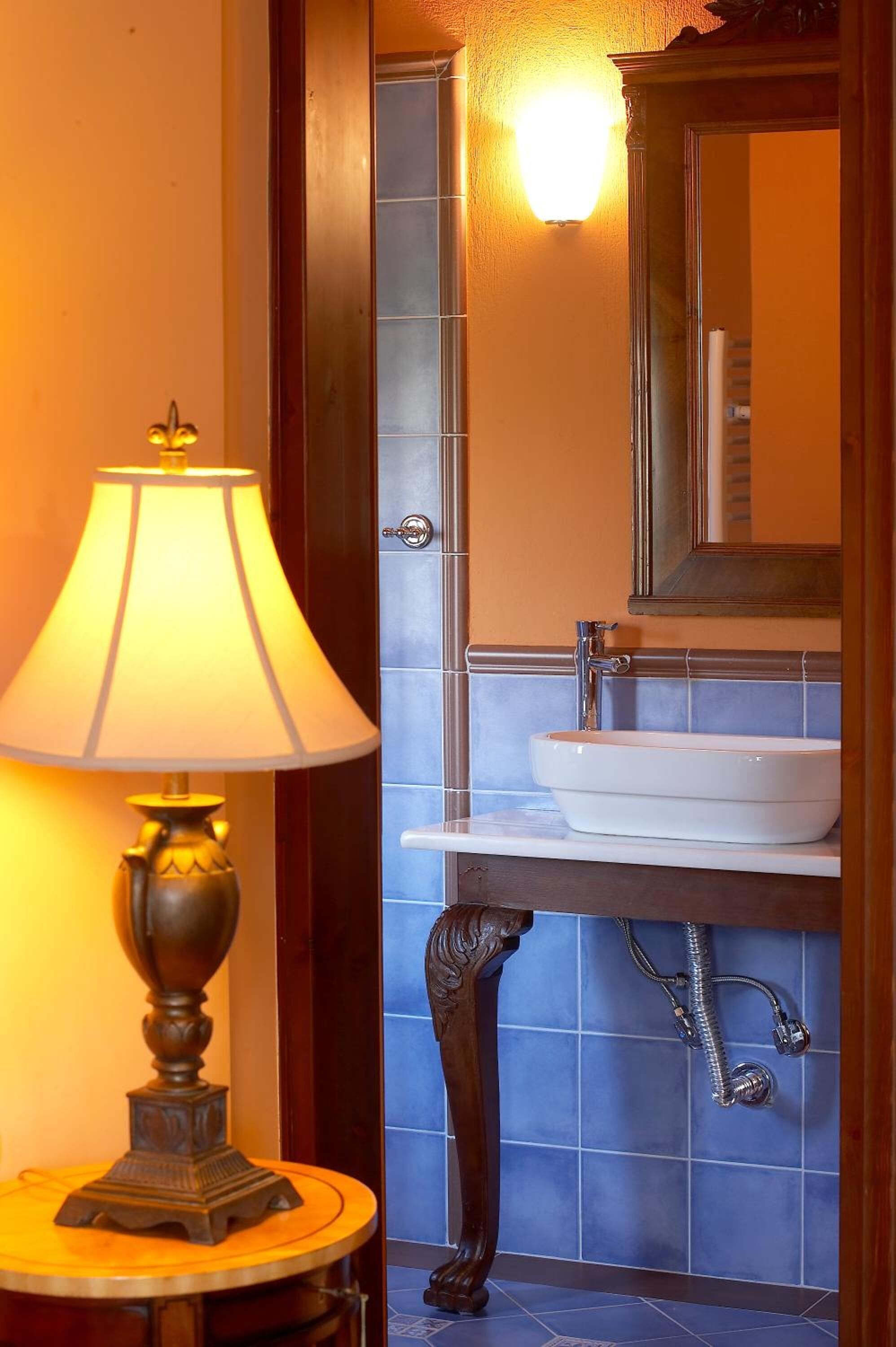 A bathroom with a white sink, a mirror above it, and a wall-mounted shower.