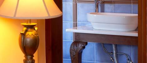 A bathroom with a white sink, a mirror above it, and a wall-mounted shower.