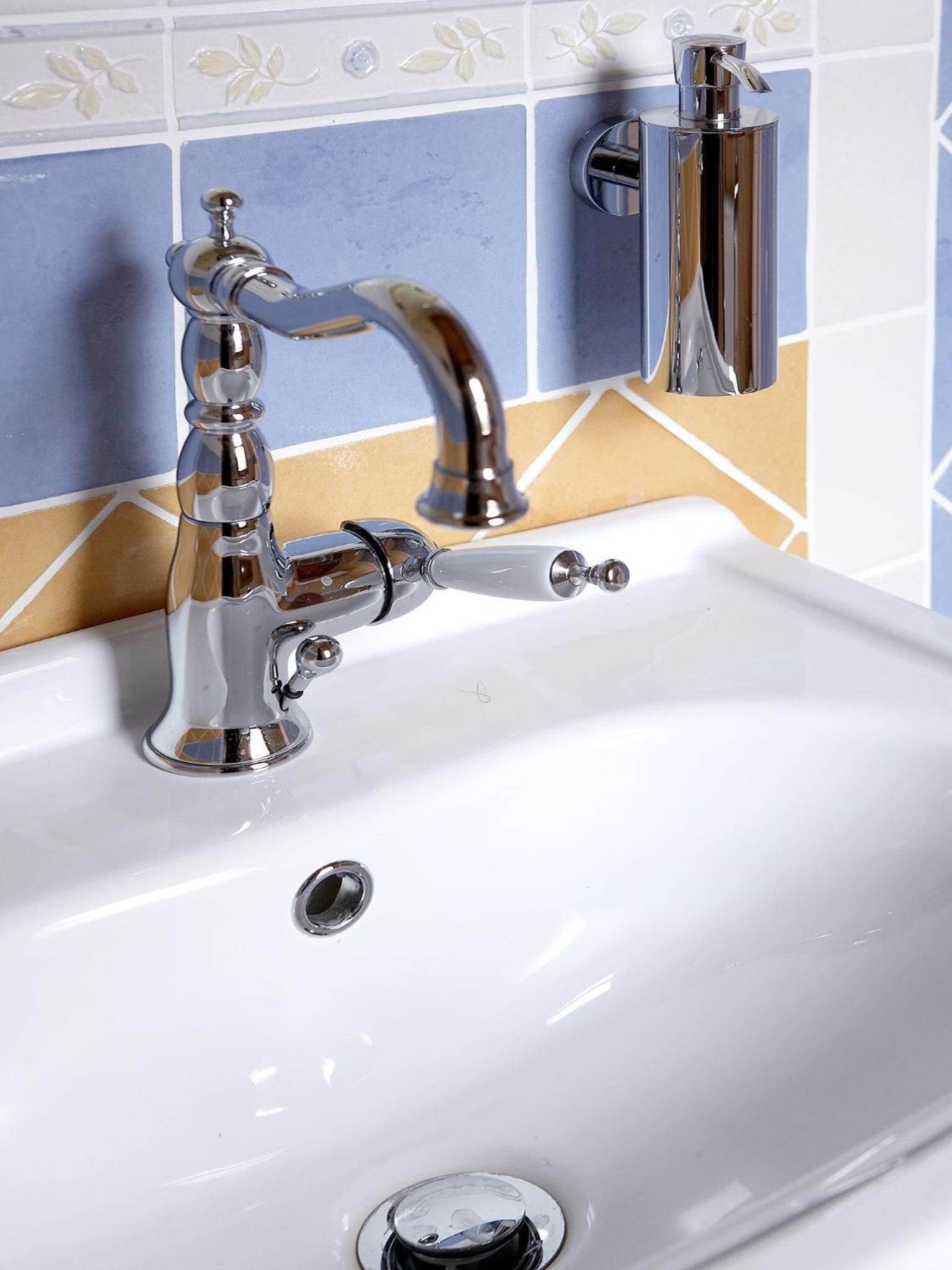 A bathroom sink with a chrome faucet and a soap dispenser.