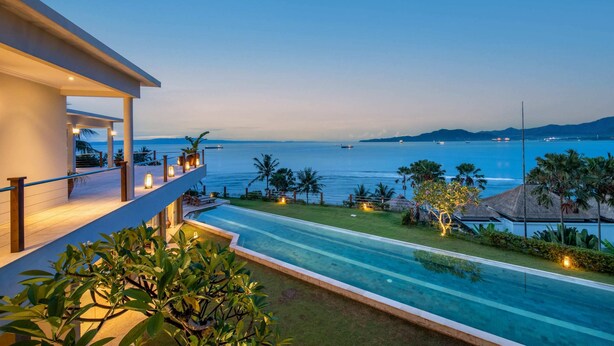 A modern hotel with a pool, a balcony overlooking the sea, and tropical landscaping. - Villa Gumamela Bali (Manggis)