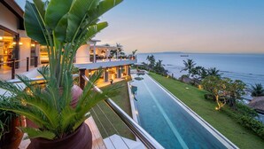 A modern resort with a swimming pool, a dining area, and a view of the ocean. - Villa Gumamela Bali (Manggis)