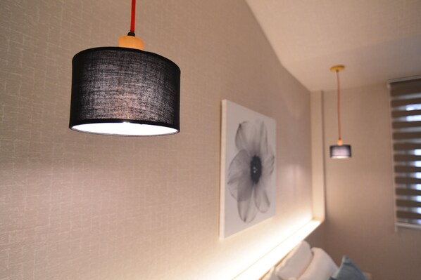 A room with a hanging lamp, a framed artwork, and a window with blinds.