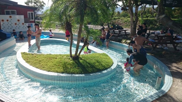 Ein Pool mit gefliestem Rand und einer Rasenfläche in der Mitte.