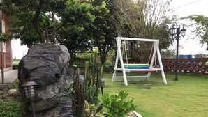 Ein Garten mit Stein, Kaktus und Schaukel.