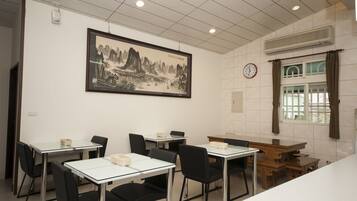 Un comedor con mesas y sillas, un reloj en la pared y un cuadro enmarcado.