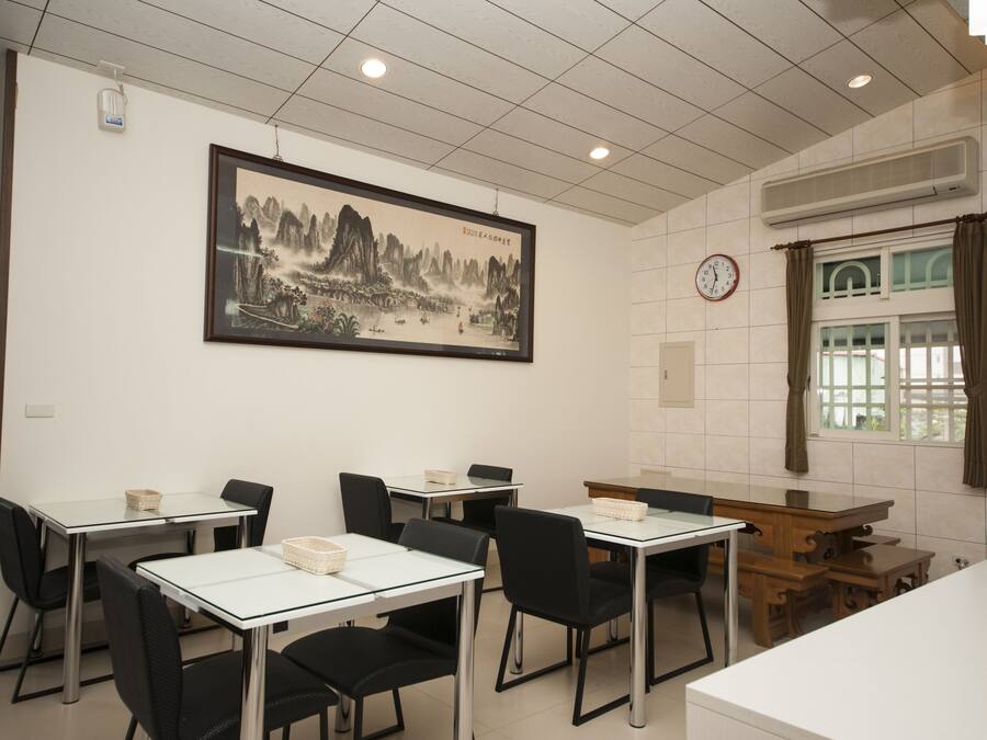 A dining area with tables and chairs, a clock on the wall, and a framed painting.