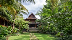 Un jardín tropical que conduce a una casa de madera con un sendero de piedra.
