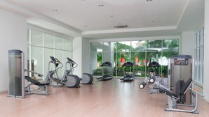 Una palestra moderna con diverse attrezzature per esercizi, ampie finestre e vista sul verde circostante.