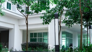 Un edificio moderno con un cortile che include una zona relax, alberi e un elemento d'acqua.