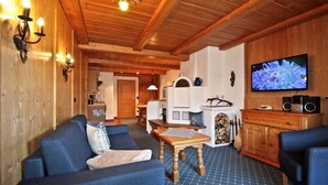 A cozy living room with a sofa, a coffee table, and a TV mounted on the wall. - Alpenpanorama Vacation Rental, 68 square meters, with balcony, kitchen, Wi-Fi (Ruhpolding)