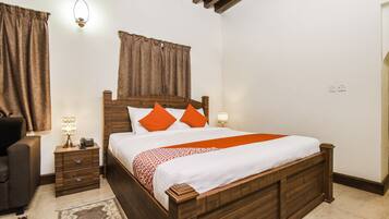 A bedroom with a wooden bed, two bedside tables, a nightstand, a lamp, and a chair.
