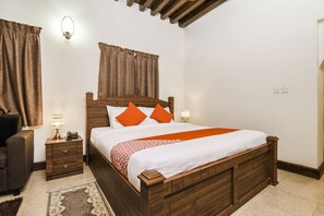 A bedroom with a wooden bed, two bedside tables, a nightstand, a lamp, and a chair. -  Capital O160 Lumbini Dream Garden Guest House LLC (Dubai)