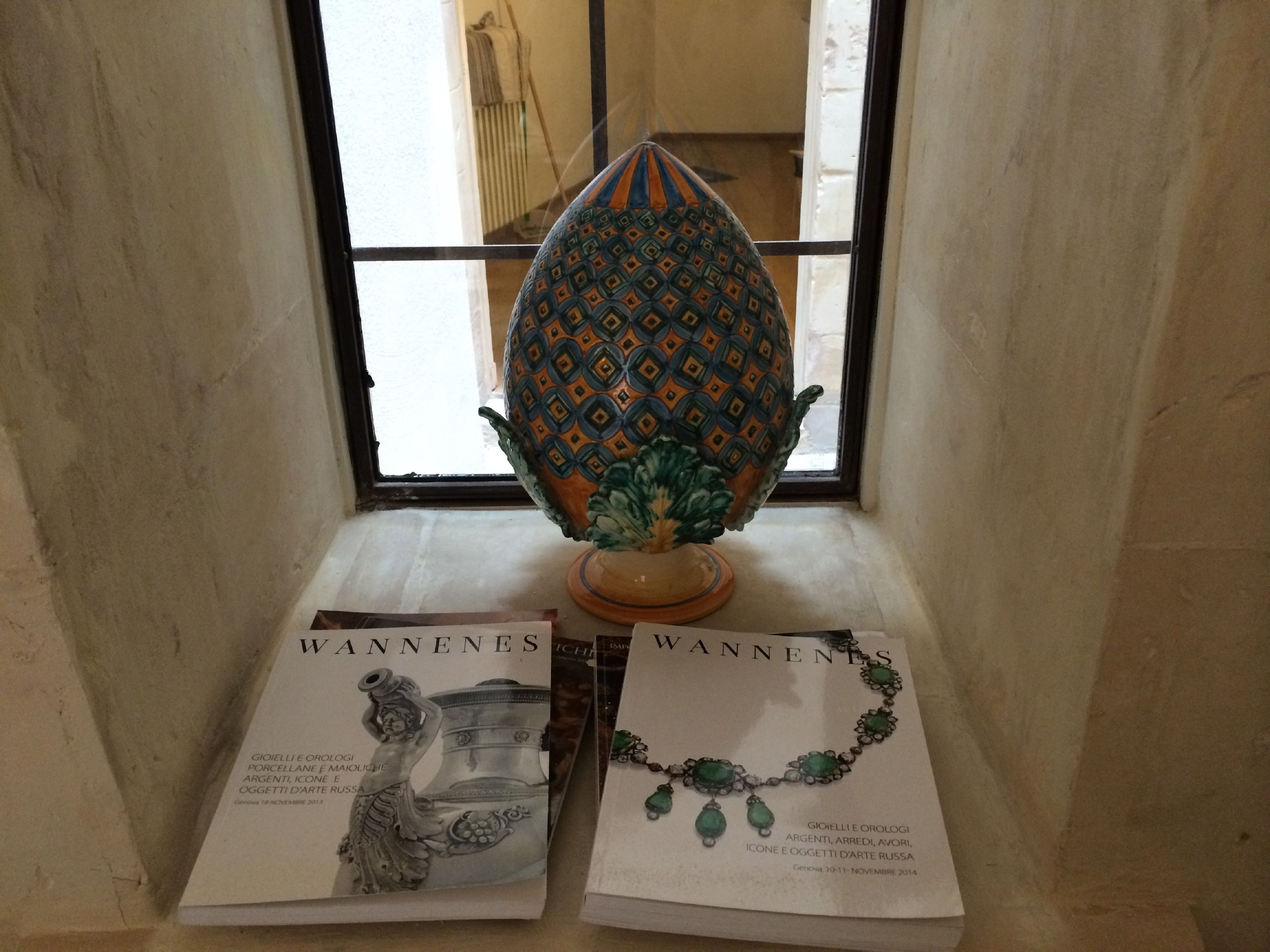 A window with a decorative ceramic piece and two informational brochures on a ledge.