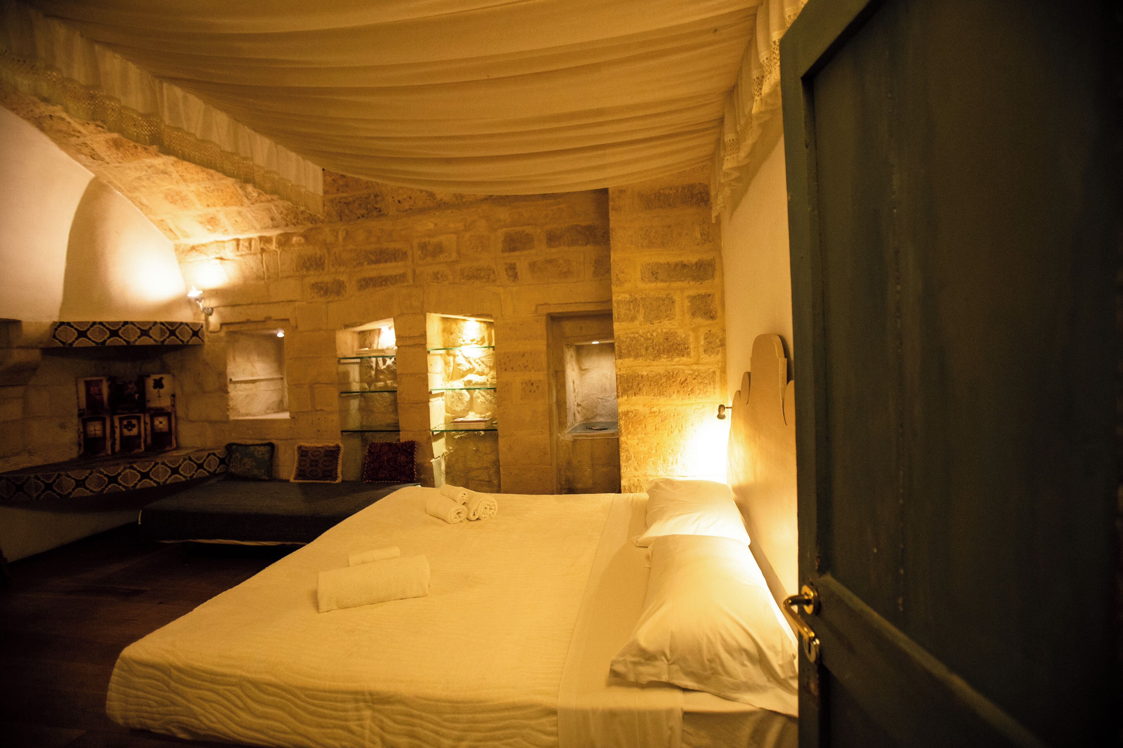 A room with a bed, a door, and stone walls.