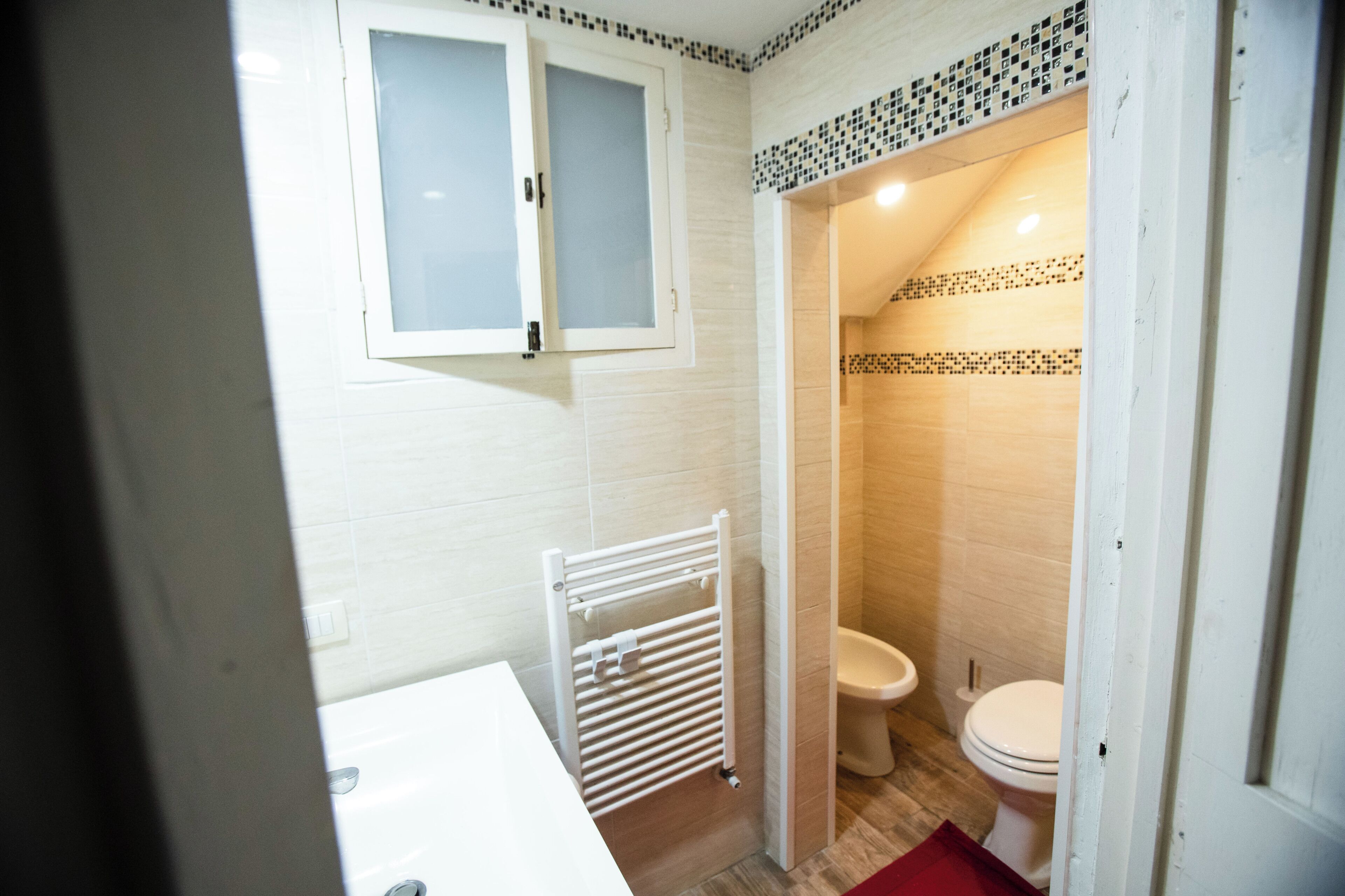 A bathroom with a white radiator, a toilet, and a shower area.