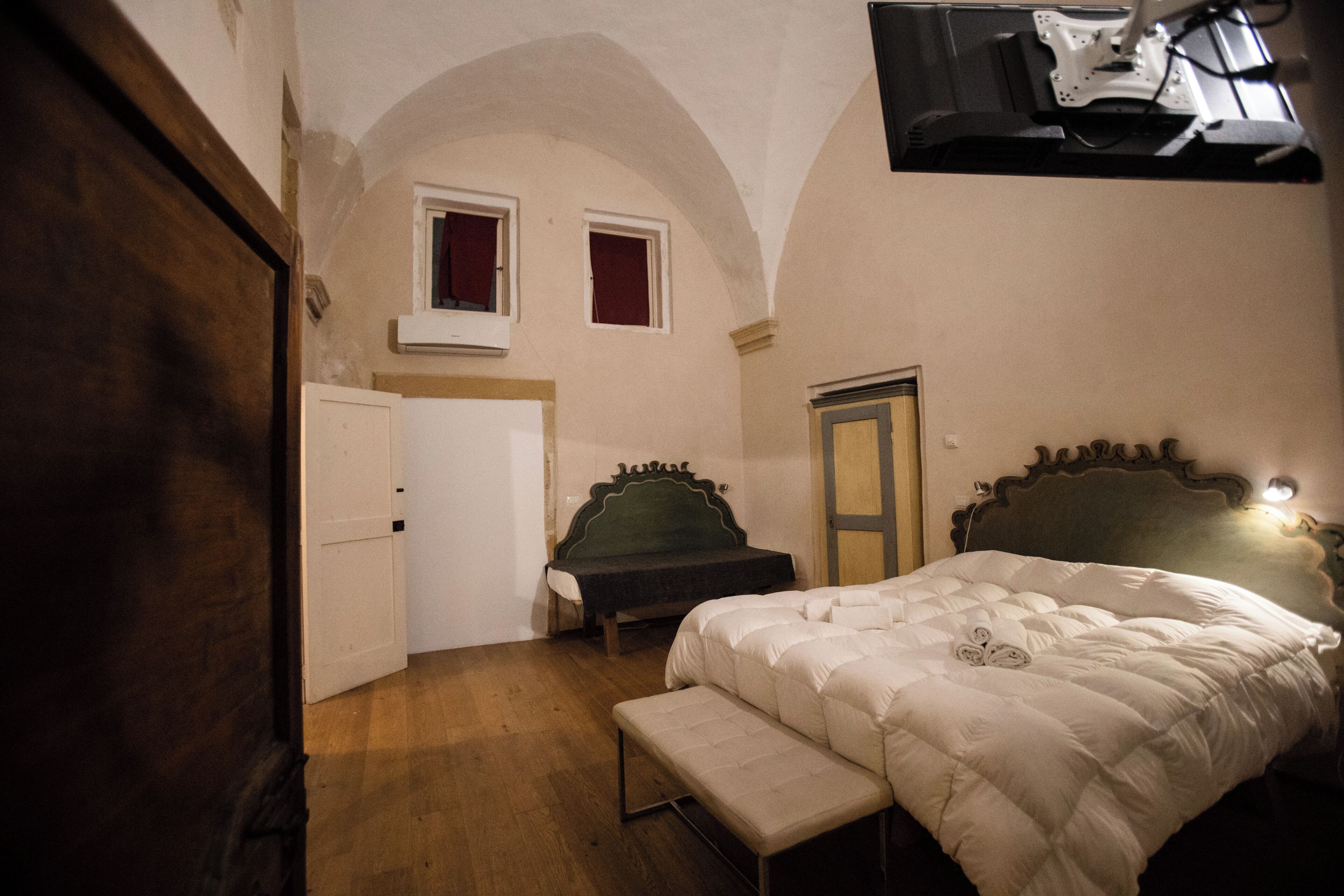 A bedroom with a bed, a bench, a wardrobe, and a door.