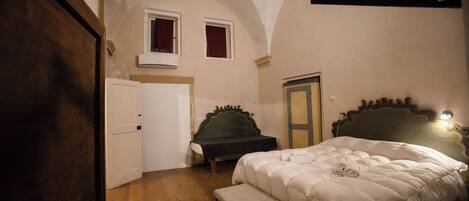 A bedroom with a bed, a bench, a wardrobe, and a door.